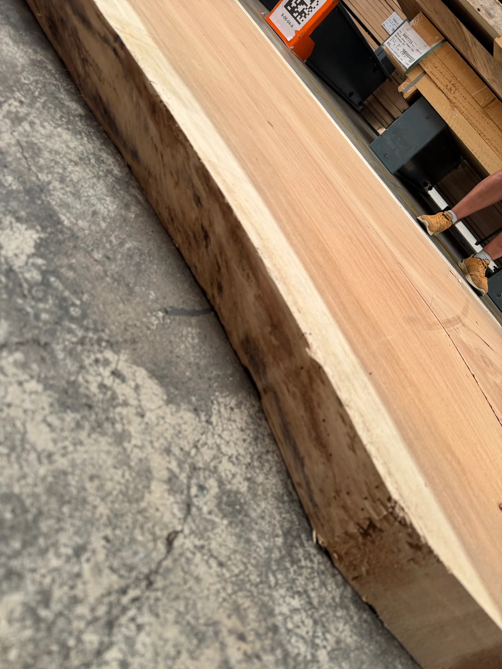 Angled edge view of the Saman slab showing its thickness, live-edge bark line, and warm face grain.